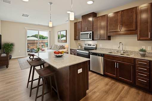 a kitchen with wooden cabinets and a marble counter top at The Quill 55+ Apartments, Hastings, MN, 55033