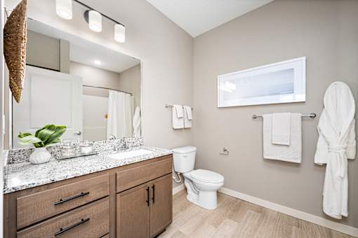 A bathroom with a white toilet and a white robe hanging on the wall.