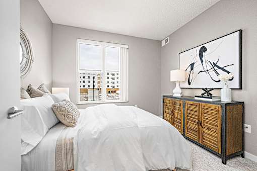 A bedroom with a large bed and a wooden cabinet.