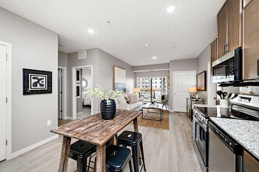 A modern kitchen with a wooden table and bar stools.
