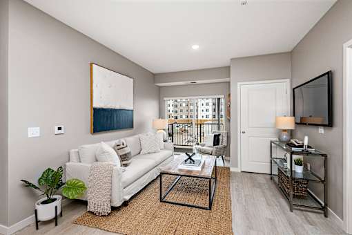 A living room with a white couch and a painting on the wall.