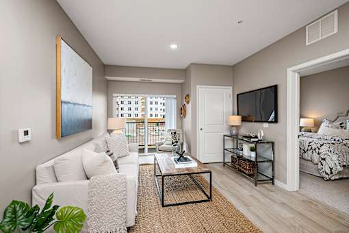 A living room with a white couch and a painting on the wall.