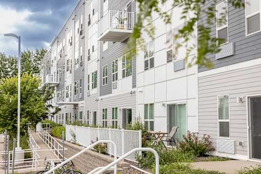 a large white apartment building with stairs and a fence at Technology Park Apartments, Minnesota, 55901