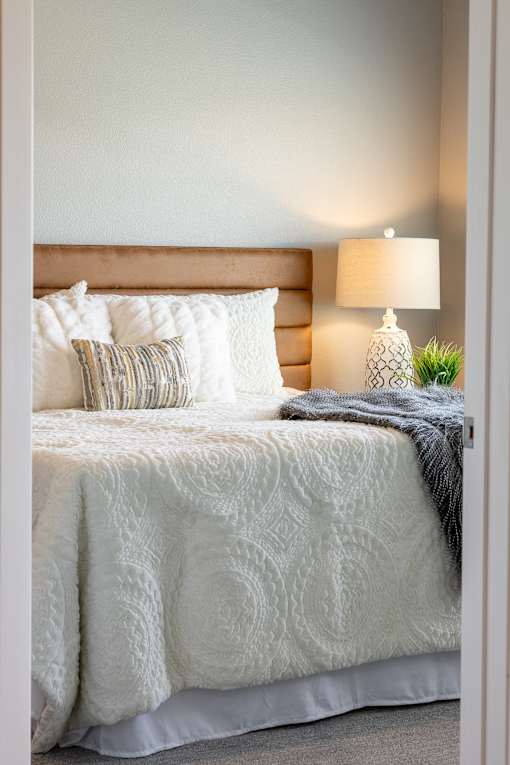 a bedroom with a bed and pillows and a lamp at Technology Park Apartments, Minnesota, 55901