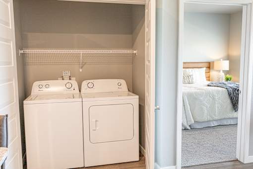 a room with a washer and dryer and a bedroom with a bed at Technology Park Apartments, Minnesota