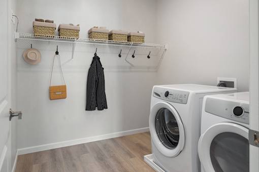 a washer and dryer in a laundry room with a white wall at The Landing at Amber Fields Apartments, Rosemount, 55068