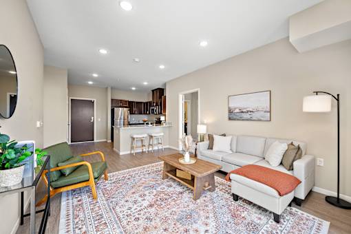 A living room with a rug on the floor and a couch with pillows at The Winslow 62+ Apartments, West St Paul, 55118