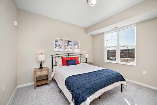 A bedroom with a bed, nightstand, and pictures on the wall at The Winslow 62+ Apartments, West St Paul, MN, 55118
