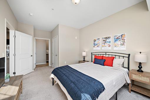 A bedroom with a bed, nightstand, and a painting on the wall at The Winslow 62+ Apartments, West St Paul, MN