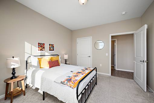 A bedroom with a bed, a nightstand, and a mirror at The Winslow 62+ Apartments, West St Paul, 55118