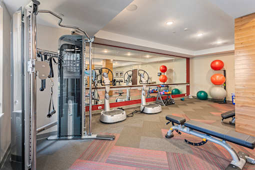 a gym with cardio equipment and weights on the floor at The Winslow 62+ Apartments, West St Paul, 55118