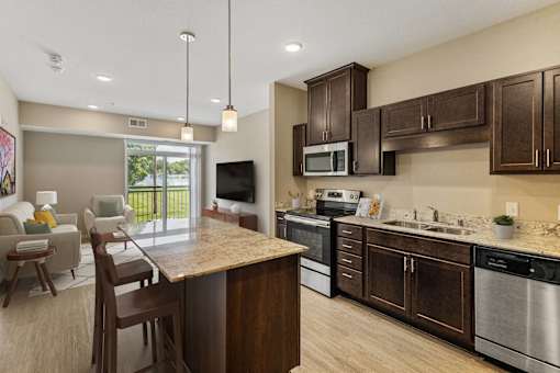 an open kitchen and living room with a table and chairs at The Winslow 62+ Apartments, West St Paul, Minnesota