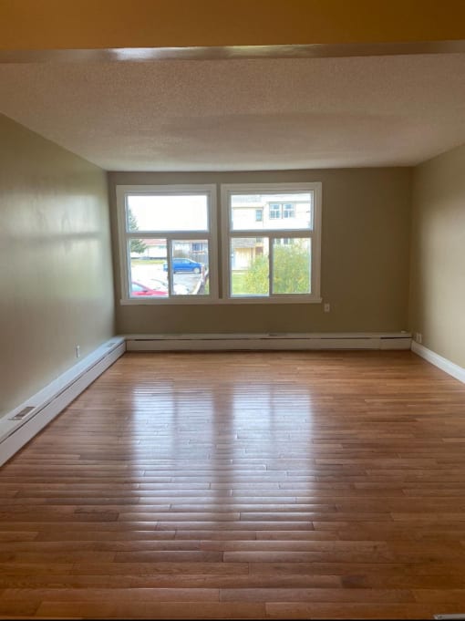 an empty living room with wooden floors and a window