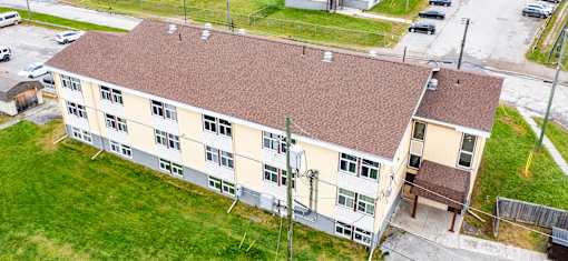 A building with a brown roof and a parking lot in front.