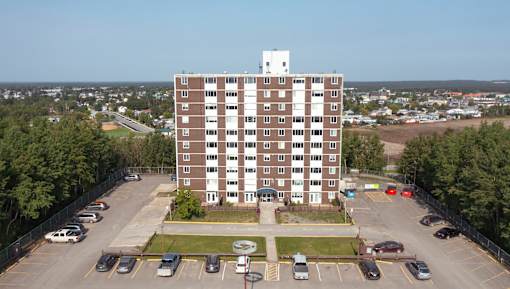 A large brown building with a white tower on top is surrounded by a parking lot.