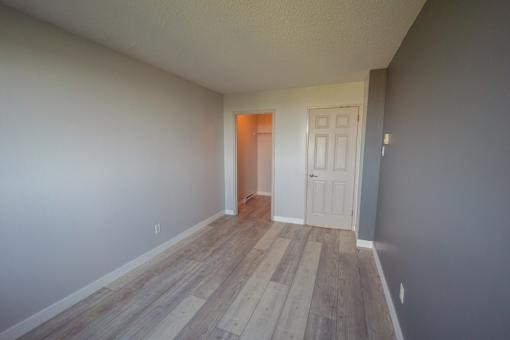 A room with a white door and wooden flooring.