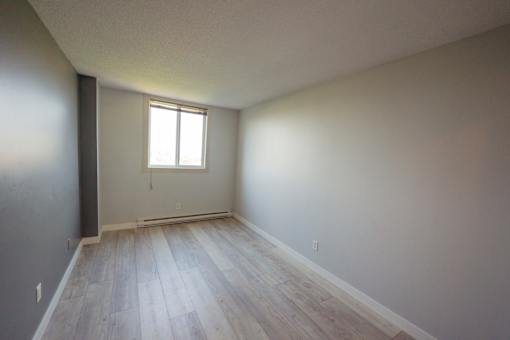 A room with a window and wooden flooring.