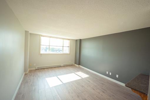 A room with a window and wooden flooring.