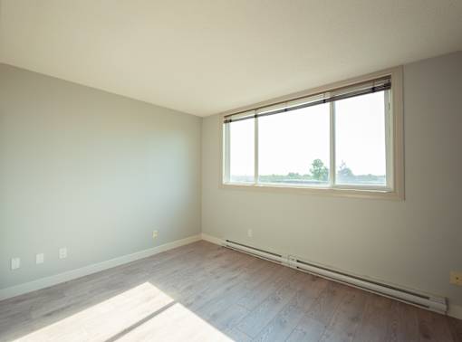 A room with a window and a wooden floor.