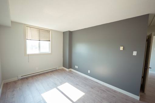 A room with a window and a white rug on the floor.