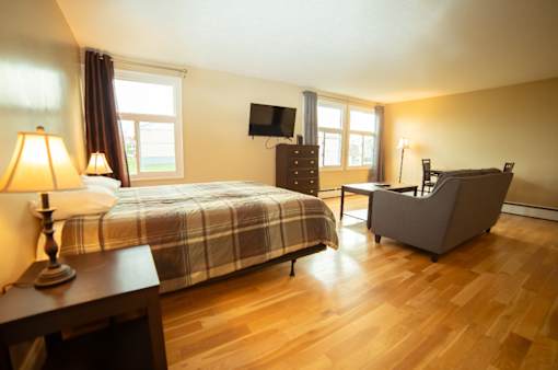 A bedroom with a bed, chair, and lamp.