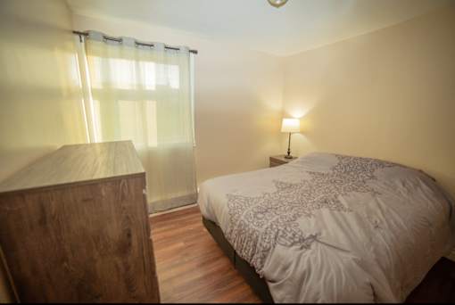 A bedroom with a bed, nightstand, and lamp.