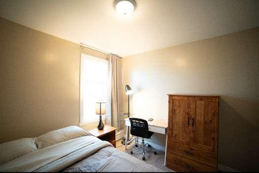 A bedroom with a bed, desk, and chair.