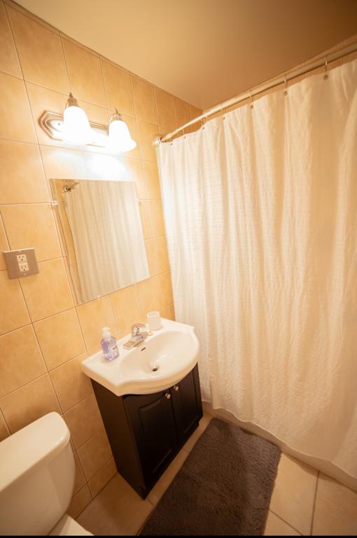 A small bathroom with a toilet, sink, and shower curtain.