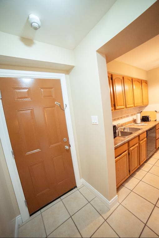 A brown door is in a hallway leading to a kitchen.