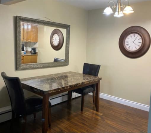 a dining room with a table and chairs and a clock on the wall