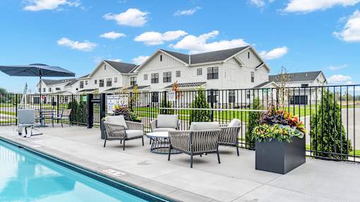 A poolside area with lounge chairs and a house in the background.