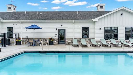 A pool in front of a white building with a black fence around it.