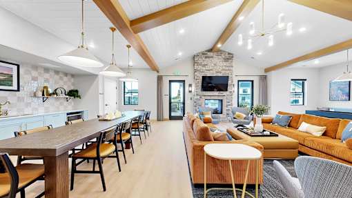 A modern living room with a wooden dining table and a stone fireplace.