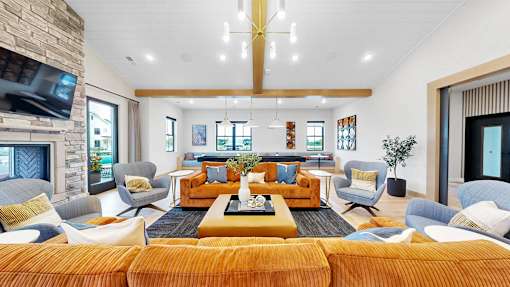 A living room with a stone fireplace and a large orange sofa.