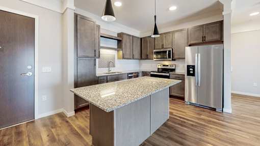 A modern kitchen with a granite countertop and stainless steel appliances.