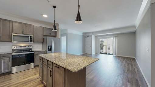 A modern kitchen with a granite countertop and stainless steel appliances.