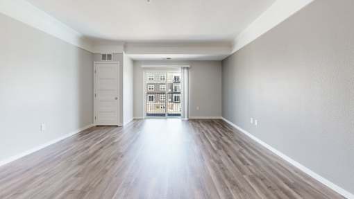 A room with wooden floors and a white door leading to a balcony.