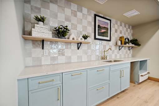 A kitchen with blue cabinets and a checkered backsplash.