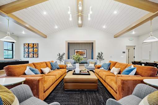 A living room with orange couches and a black rug.