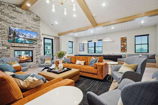 A living room with a stone fireplace and a large flat screen TV mounted above it.