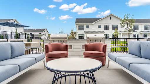 A white table with a red chair and a blue chair in front of a white building.