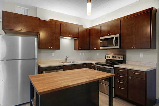 A kitchen with brown cabinets and a wooden island.