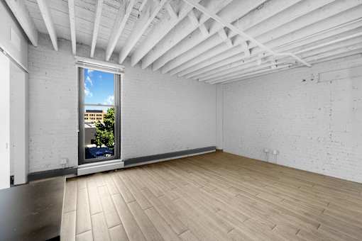 A room with a window and wooden flooring.