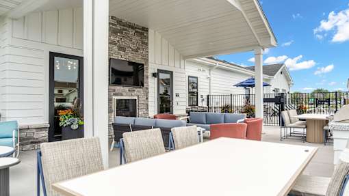 A white building with a stone fireplace and a white table and chairs outside.
