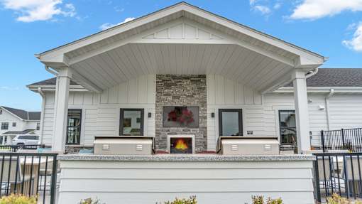A white house with a stone fireplace on the front porch.