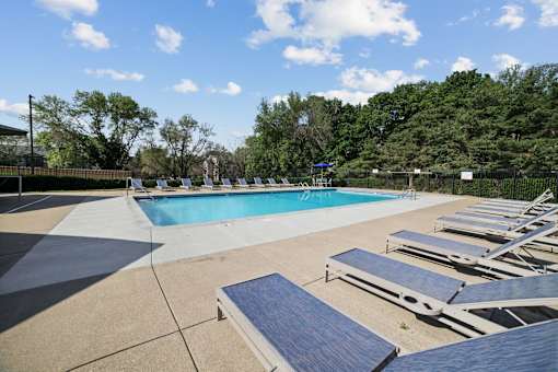 a pool with lounge chairs and trees in the background at Audenn Apartments, Bloomington, MN, 55438