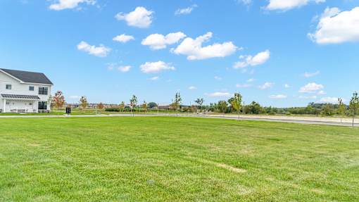 A large grassy field with a house in the background.