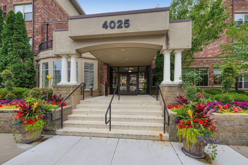 the front of a building with stairs and a entrance with flowers