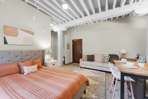 A bedroom with a bed, a couch, and a dining table.