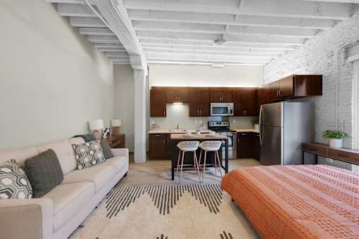 A modern living room with a white couch and a kitchen area in the background.